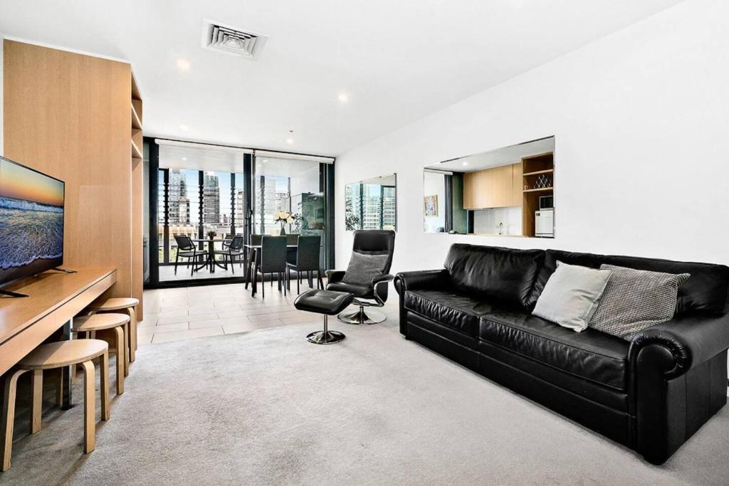 uma sala de estar com um sofá de couro preto e uma cozinha em The Patio Place near Crown Casino with Parking em Melbourne