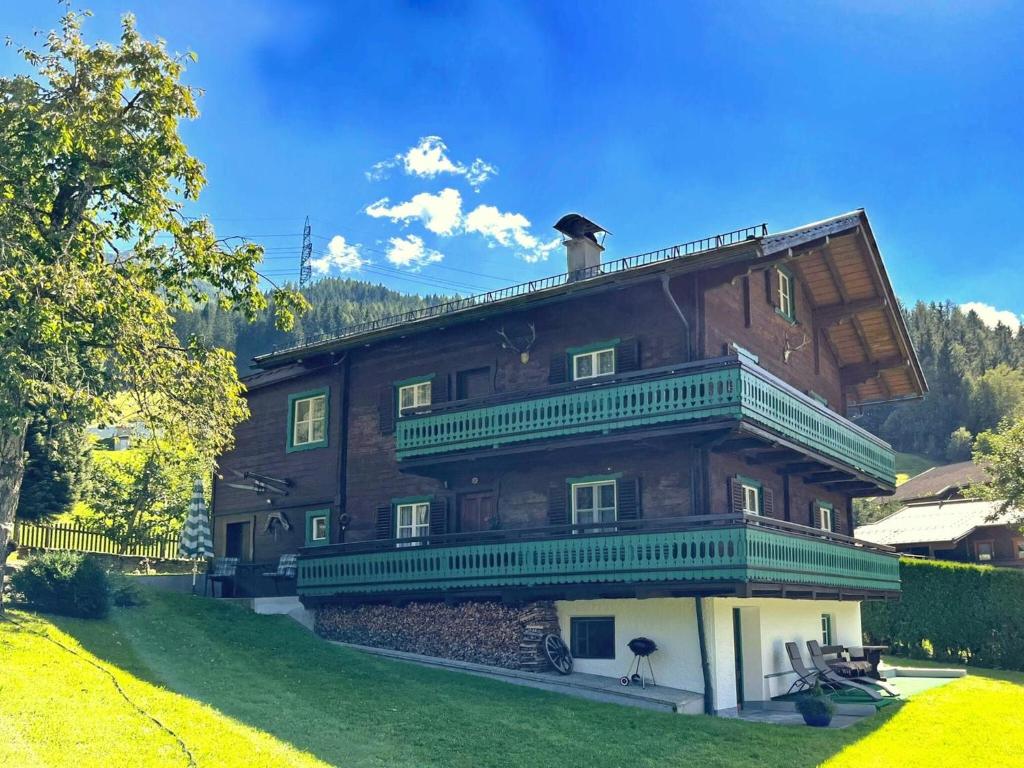 a large wooden house with green balconies on a yard at Austrian chalet in Bramberg with sauna in Bramberg am Wildkogel