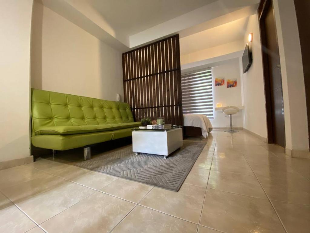 a living room with a green couch and a table at APARTAESTUDIO EN SAN FERNANDO in Cali