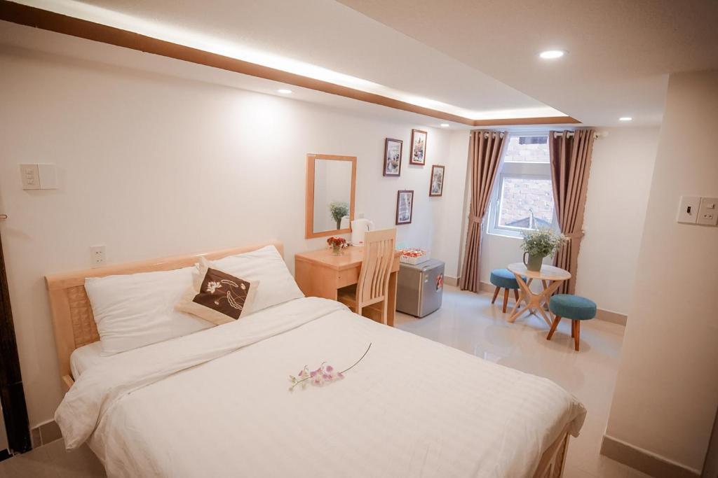 a bedroom with a white bed and a table and chairs at Thanh Thanh 2 Hotel in Da Lat
