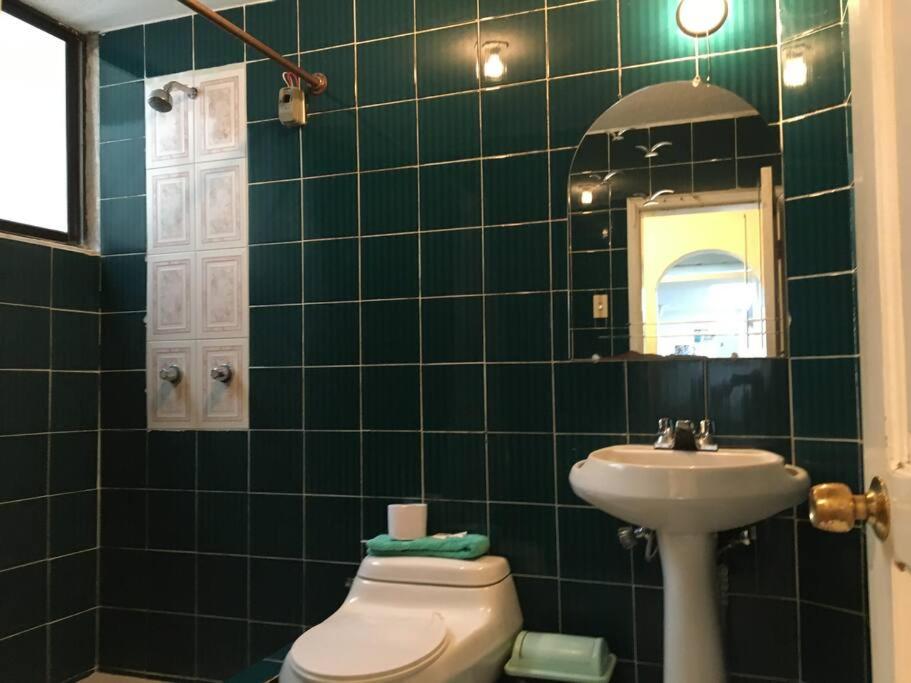 a green tiled bathroom with a toilet and a sink at Mi Casa en Rio in Riobamba