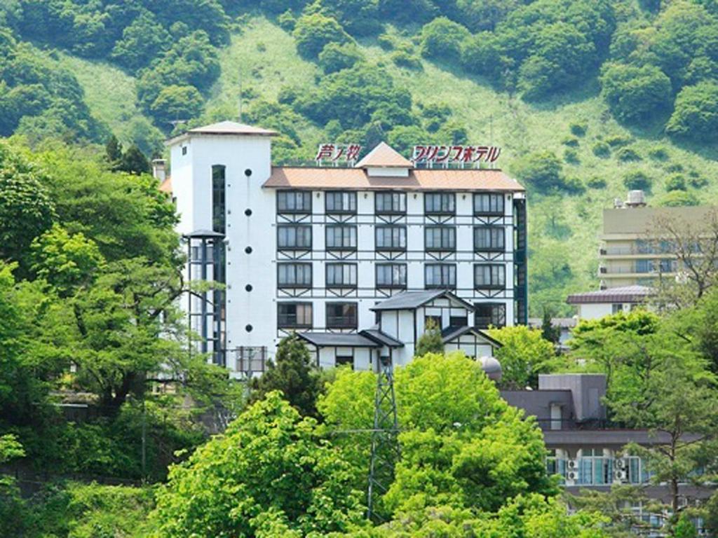 a large white building in front of a mountain at Ashinomaki Prince Hotel in Aizuwakamatsu
