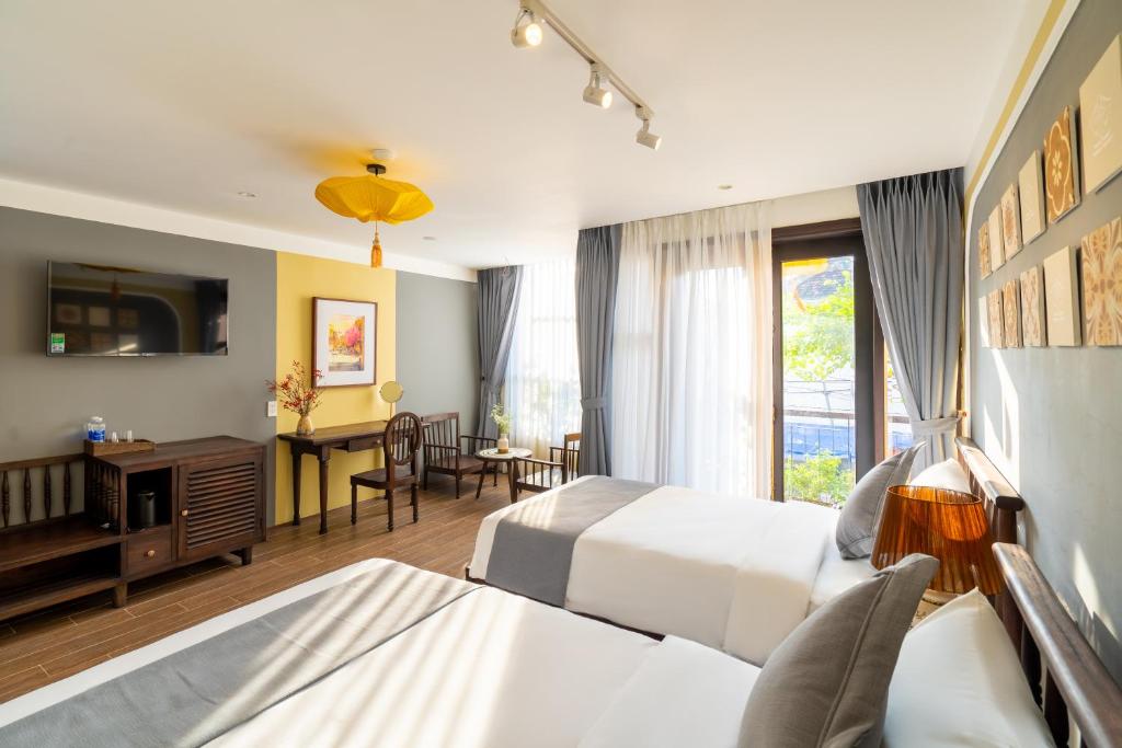 a hotel room with two beds and a living room at Hoianan Boutique Hotel in Hoi An