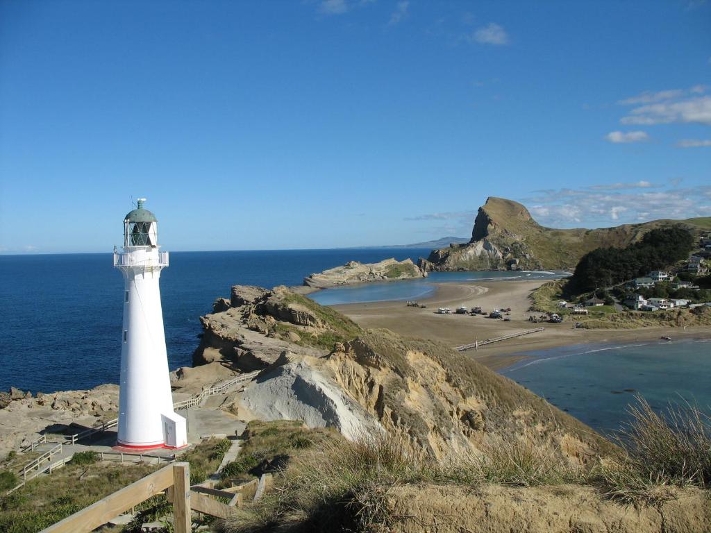 a lighthouse on a cliff next to a beach at Castlepoint Holiday Park & Motels in Castlepoint