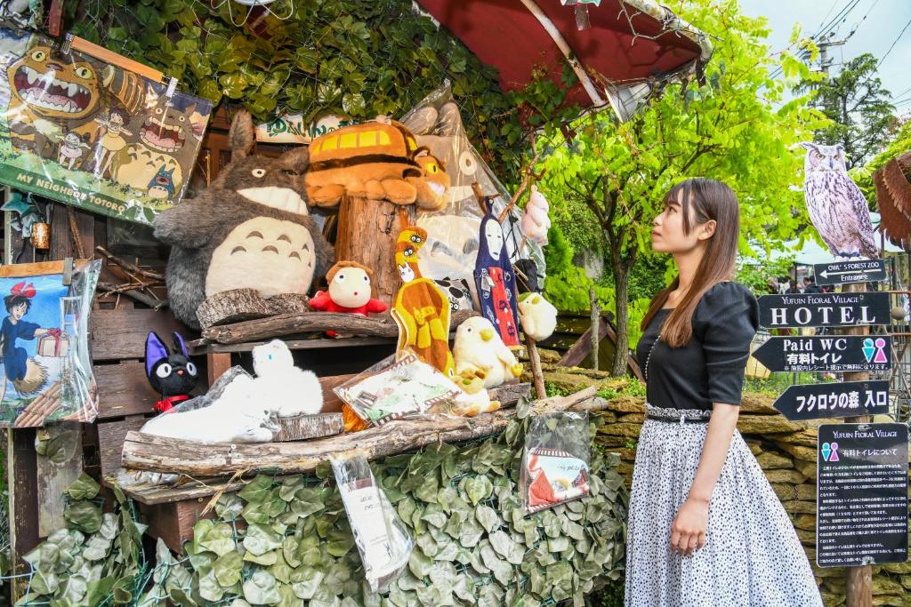 een vrouw die voor een voorstelling van knuffeldieren staat bij ＹＵＦＵＩＮ　ＦＬＯＲＡＬ　ＶＩＬＬＡＧＥ　ＨＯＴＥＬ in Yufu