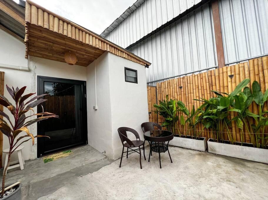 a patio with two chairs and a table in front of a building at Night Delight in Baan Tai