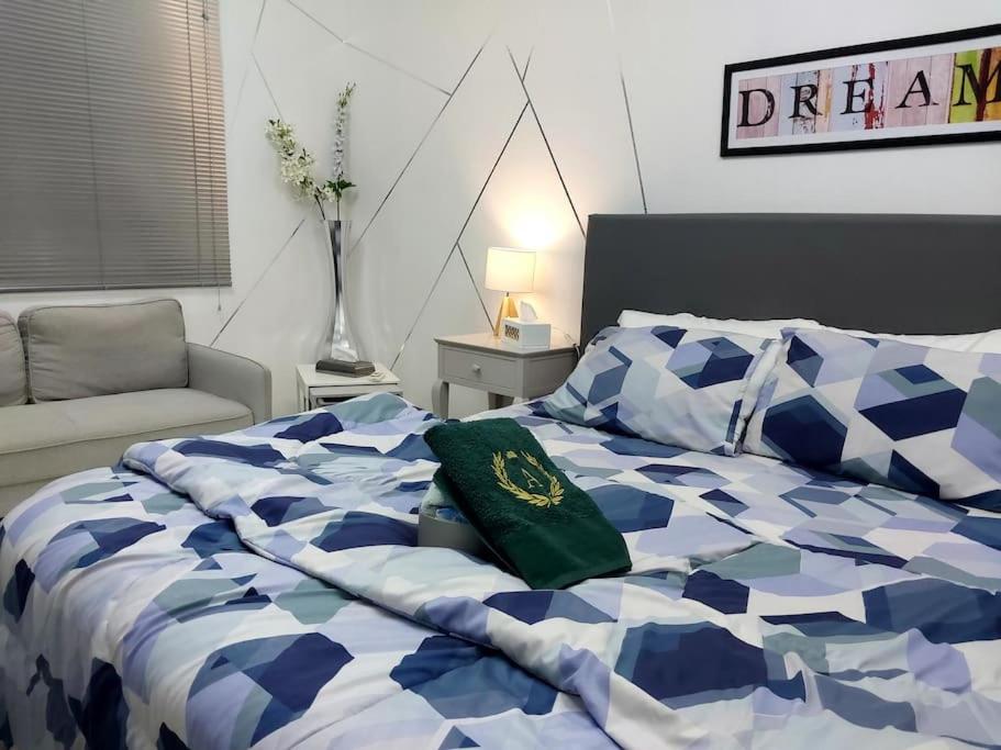 a bed with a blue and white comforter and a chair at Private Bedroom in a Home With Park View in Sharjah