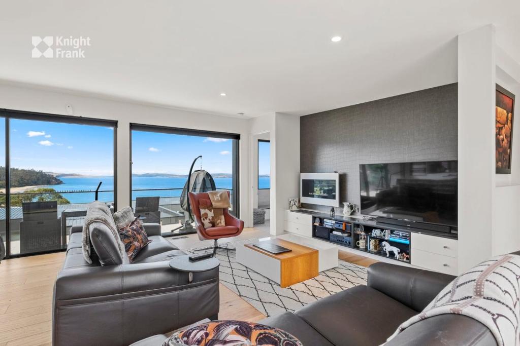 sala de estar con sofá y TV en As new beachside luxury villa with stunning views, en Kingston Beach