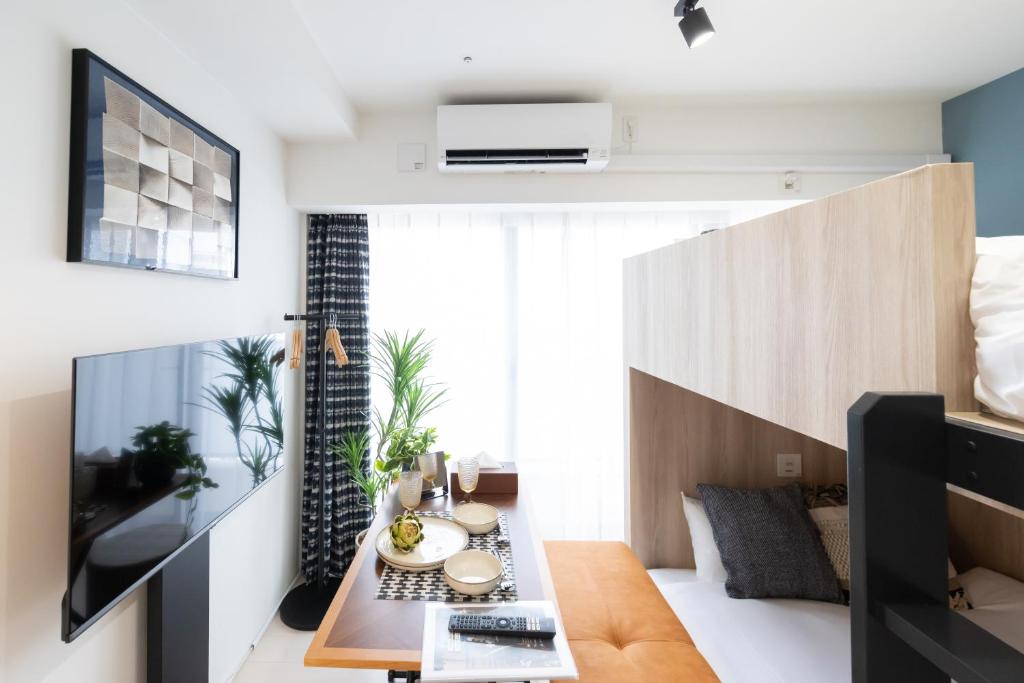 ein Wohnzimmer mit einem TV und einem Tisch in der Unterkunft Primavera Namba in Osaka