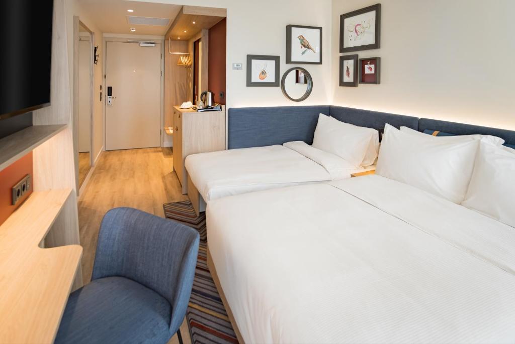 a hotel room with a large bed and a chair at Hampton by Hilton Riga Airport in Riga