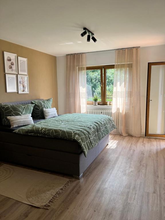 a bedroom with a bed with a green comforter and a window at Landliebe in Schonungen