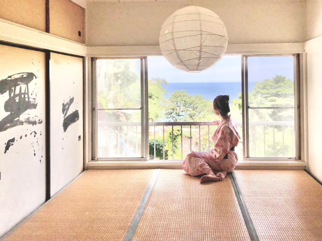 Dziewczyna siedząca na podłodze patrząca przez okno w obiekcie XXUFO w mieście Atami
