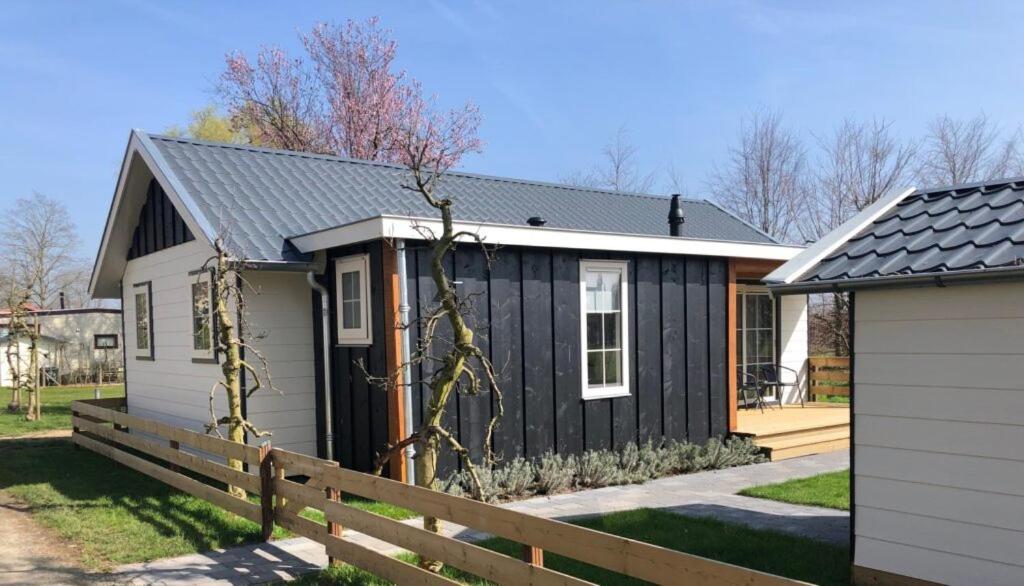 een zwart-wit tiny house met een hek bij Vakantiehuis voor 6 personen in Opheusden