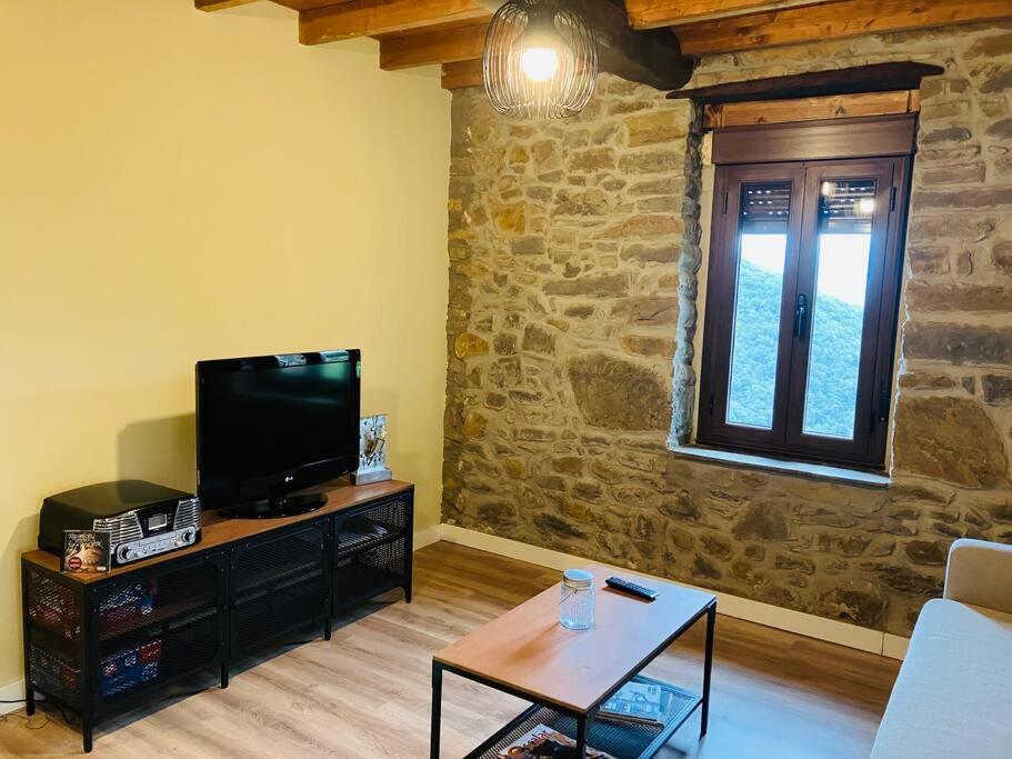 ein Wohnzimmer mit einem TV und einem Tisch in der Unterkunft La So Casa -En el corazón de Asturias in Armiello