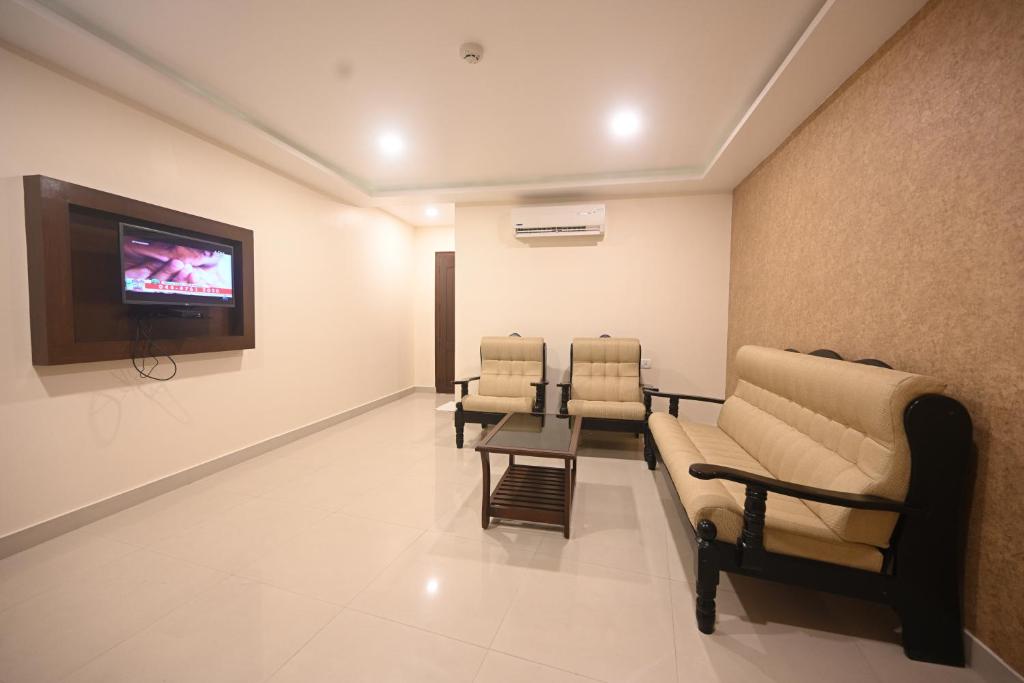 sala de estar con sillas y TV de pantalla plana en Hotel Bhagavath Gardens, en Chengannūr