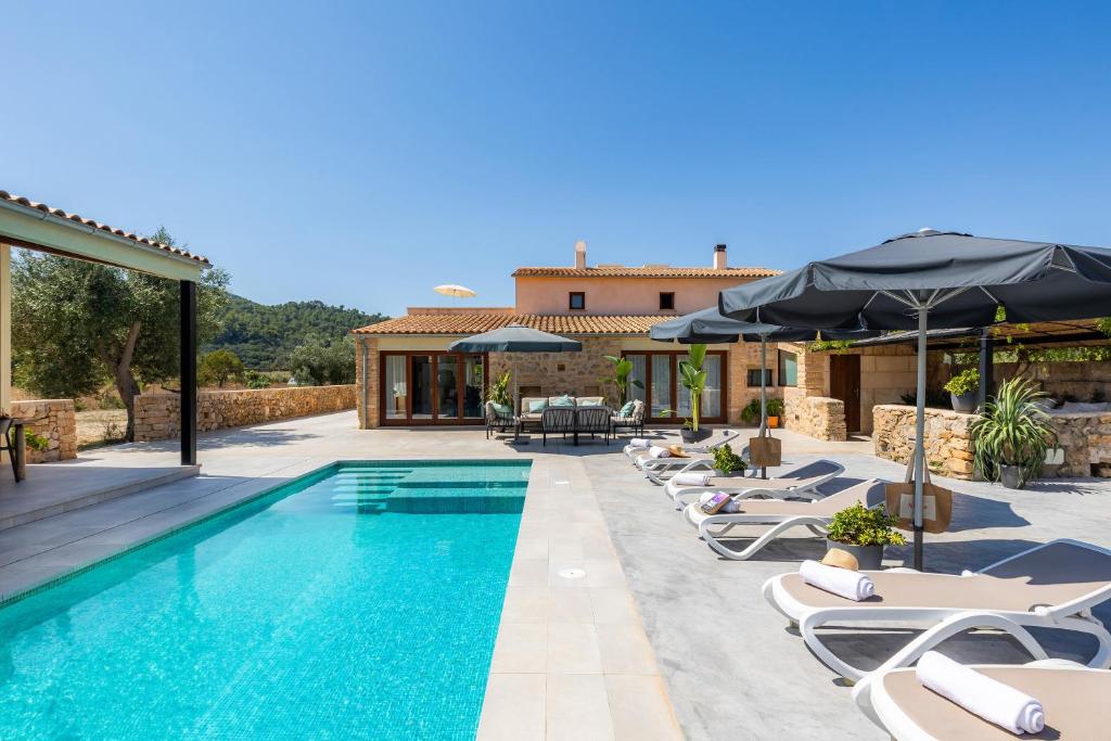 - une piscine avec des chaises et des parasols à côté d'une maison dans l'établissement Finca Can Caragol de Dalt, à Capdepera