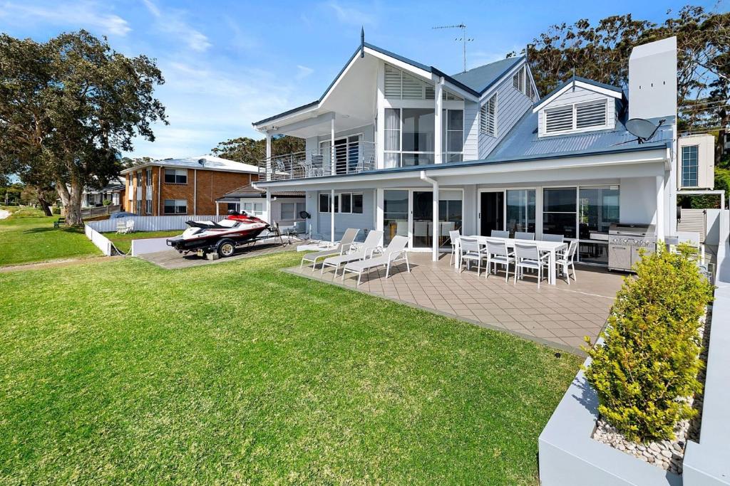 una grande casa bianca con un'auto su un patio di Waterfront Wonderland 41 Foreshore Dr stunning house with a lift linen Wi Fi and ducted air conditioning a Salamander Bay