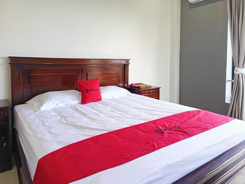 ein großes Bett mit einer roten Decke drauf in der Unterkunft RedDoorz @ Green Homestay Syariah Baubau in Baubau