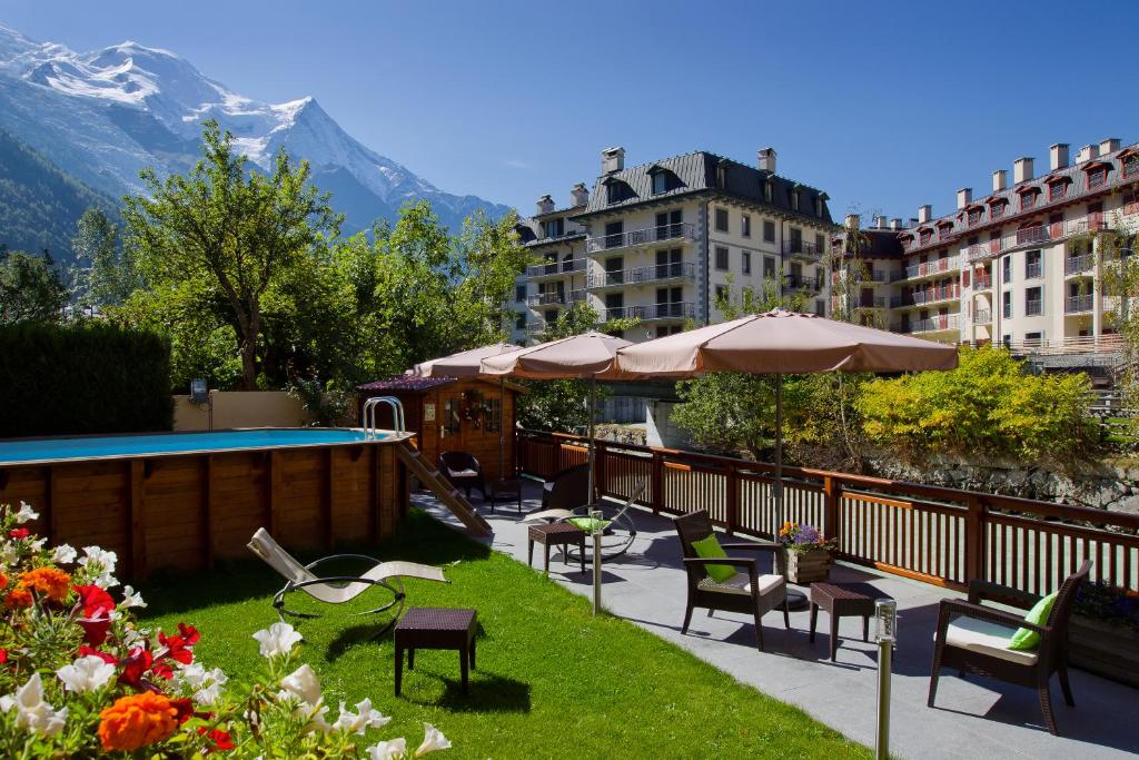 a balcony with tables and chairs and a swimming pool at Les Gourmets - Chalet Hotel in Chamonix