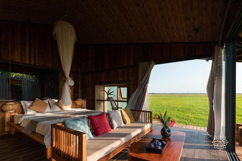 een slaapkamer met een bed, een bank en een raam bij The Ruong Resort in Vung Tau