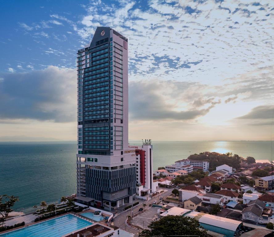 een hoog gebouw met een zwembad voor de oceaan bij Hompton Hotel by the Beach in George Town