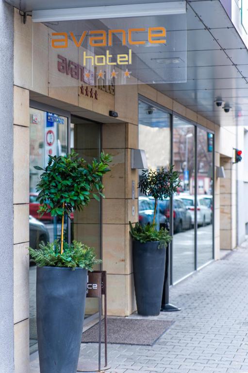 a store front with three large potted plants on the sidewalk at Hotel Avance in Bratislava