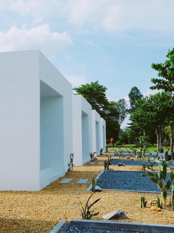 a white building on a beach with trees in the background at TJ Garden & Resort in Ban Dan Chang