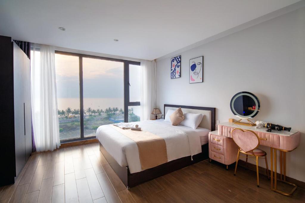 1 dormitorio con cama, escritorio y ventana en KIKOZO DA NANG Hotel, en Da Nang