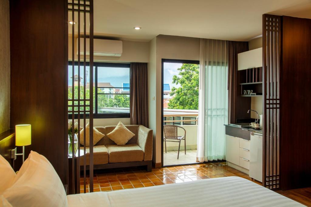 a bedroom with a bed and a chair and a balcony at The Grand Napat in Chiang Mai