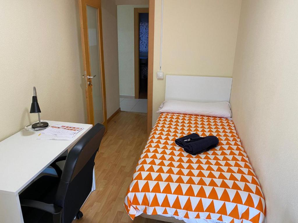 Habitación pequeña con cama, escritorio y mesa. en Room in Guest room - H Individual In Reformed Residence has wifi center num102, en Madrid