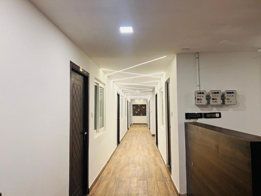 a long hallway with white walls and a wooden floor at David Residency in Madurai