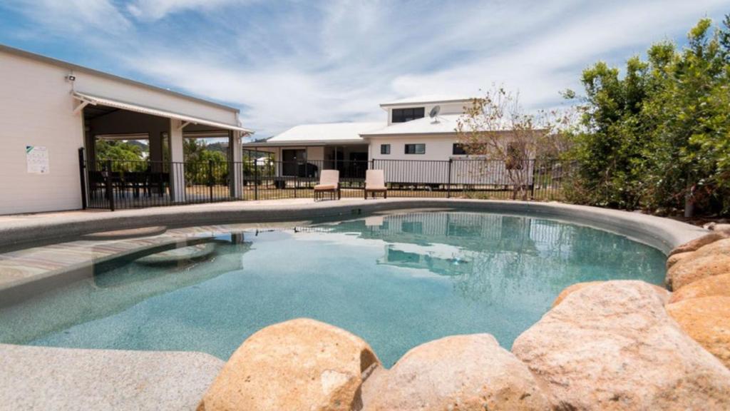 a swimming pool with rocks in front of a house at Tiramula Lodge Holiday House in Horseshoe Bay