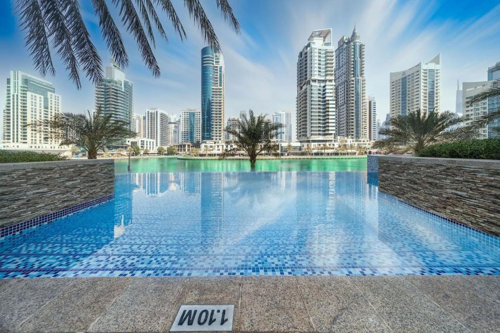 een zwembad met een skyline van de stad op de achtergrond bij Heart of the Marina - 1 BR apartment in Dubai