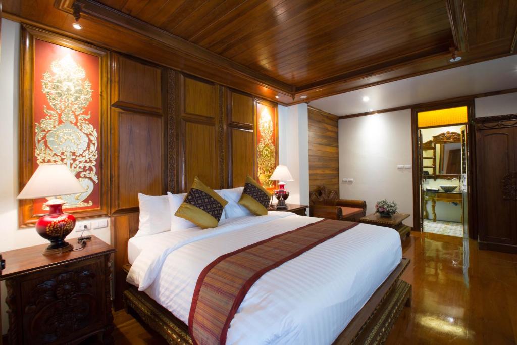 A compact, richly decorated bedroom with a carved wood headboard and dark polished finishes.