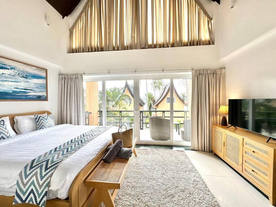 a bedroom with a large bed and a television at Sunrise Beach Villa in Ko Chang