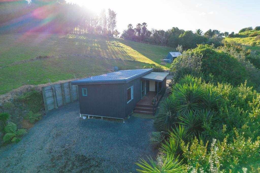 a small house on a hill with a rainbow at Seascape Cottage - Mahinepua Bay Clifftop Retreat in Mahinepua