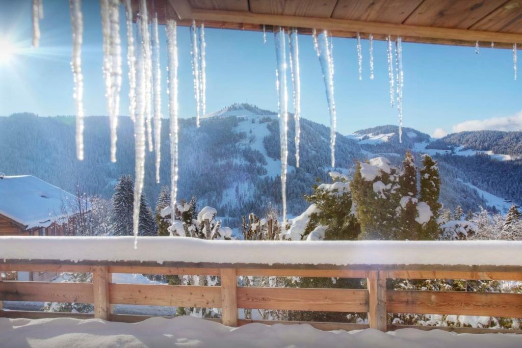 a view of snow covered mountains from a window with icicles at Chalet Zamaro - OVO Network - OVO Network in La Clusaz
