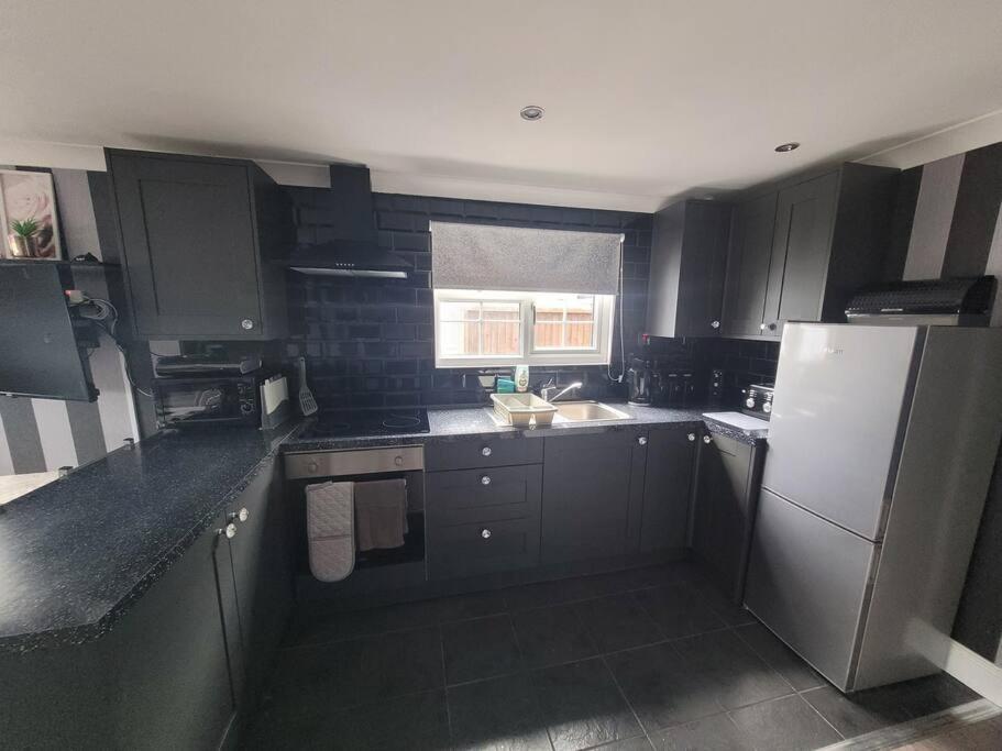 a kitchen with black cabinets and a white refrigerator at Sanity Sanctuary in Leysdown-on-Sea