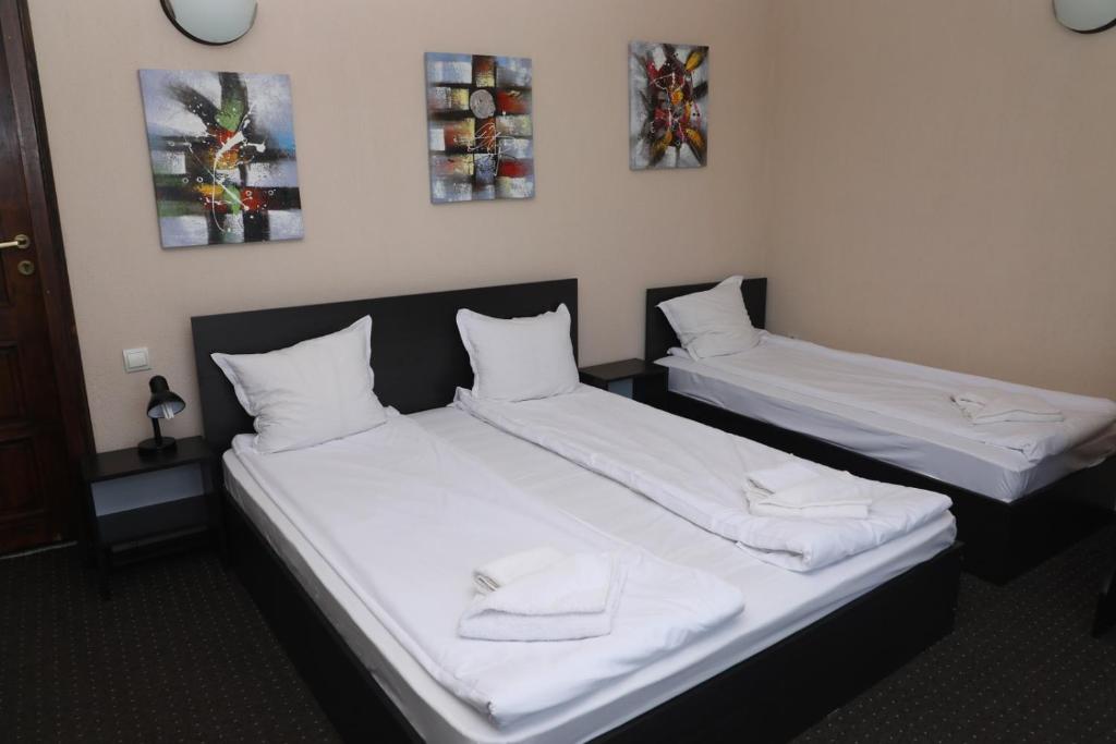 2 camas en una habitación con sábanas blancas en Опълченец, en Shipka
