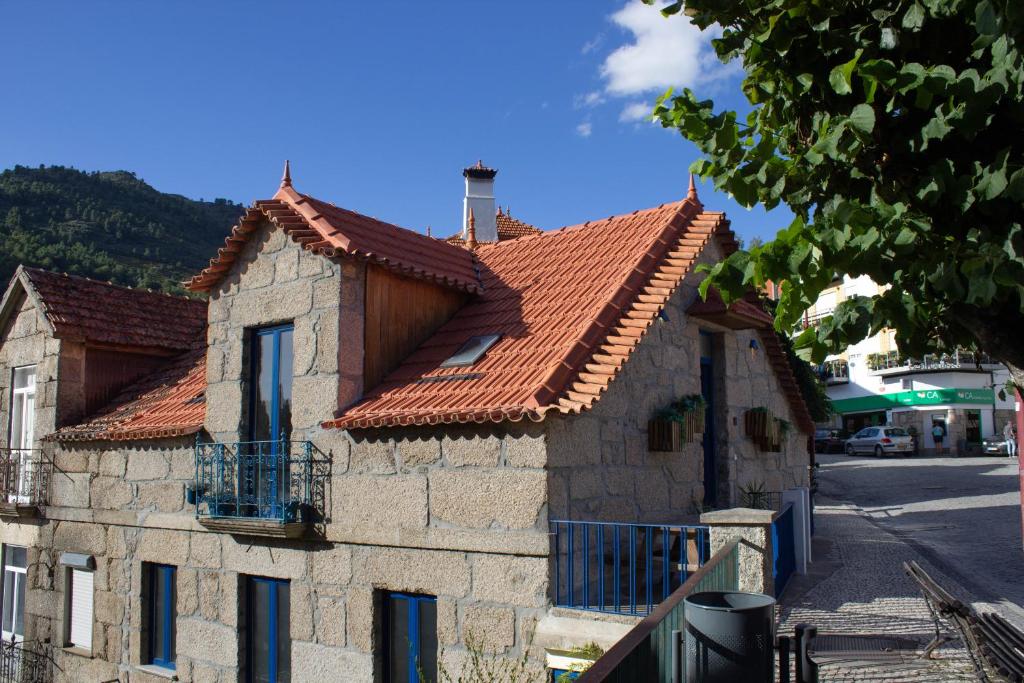 une maison en pierre avec un toit rouge dans une rue dans l'établissement Casa da Carreira de Loriga, à Loriga