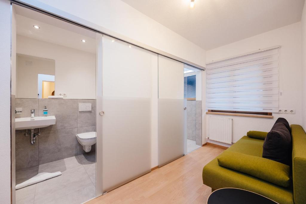 a living room with a green couch and a bathroom at Hotel Andrea in Zams