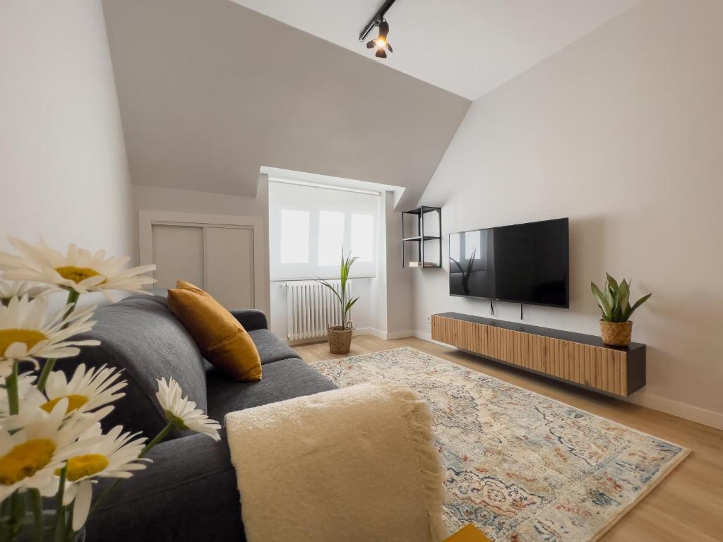 sala de estar con sofá azul y TV de pantalla plana en Hi! Burgos - SIDI - VUT-472 - Exclusivo apartamento moderno en el corazón de la ciudad, en Burgos