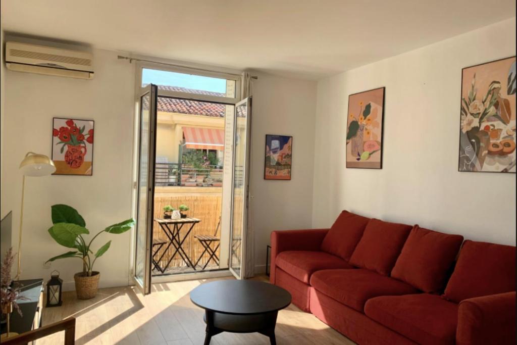 sala de estar con sofá rojo y puerta corredera de cristal en Central and blight flat with balconies, en Marsella