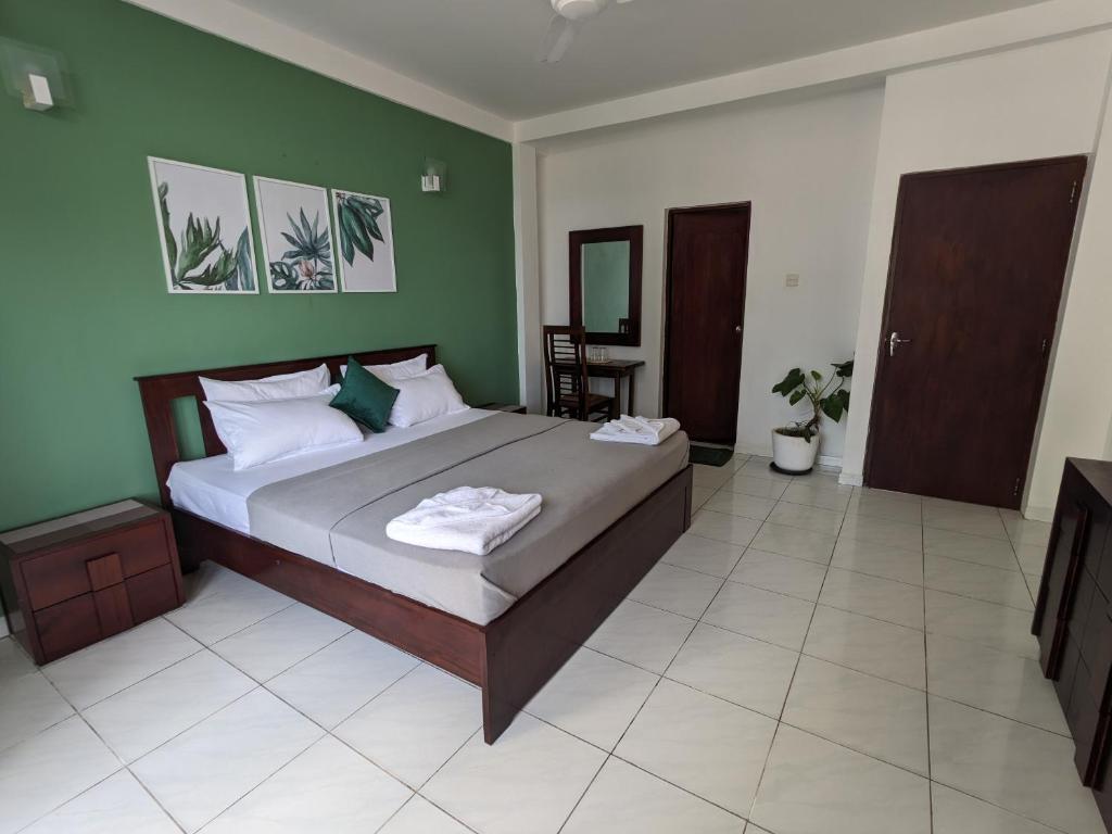 um quarto com uma cama grande e paredes verdes em Palmyrah Residencies em Colombo