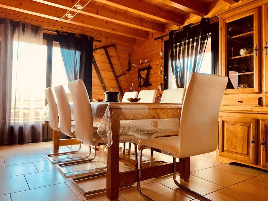ein Esszimmer mit einem Tisch und weißen Stühlen in der Unterkunft Chalet indépendant 2000m2 de terrain 3 chambres 