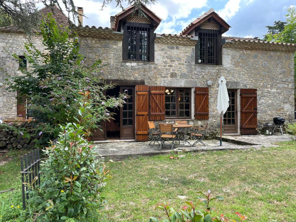 a stone house with a table and chairs in a yard at Manoir du Suquet in Bardou