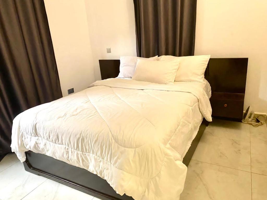 Schlafzimmer mit einem Bett mit weißer Bettwäsche und Kissen in der Unterkunft SAFARI LAKE VIEW SUITES, KITENDE in Entebbe