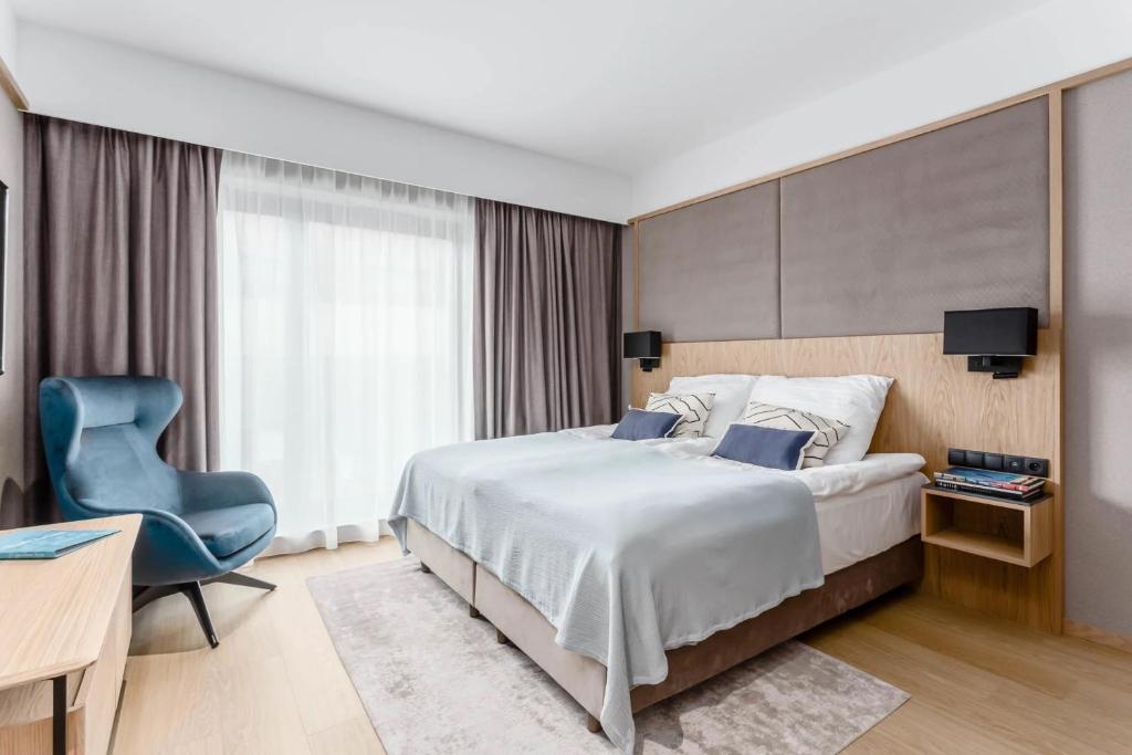 a bedroom with a large bed and a blue chair at Deo Plaza Old Town Gdańsk - Praia Apartaments in Gdańsk