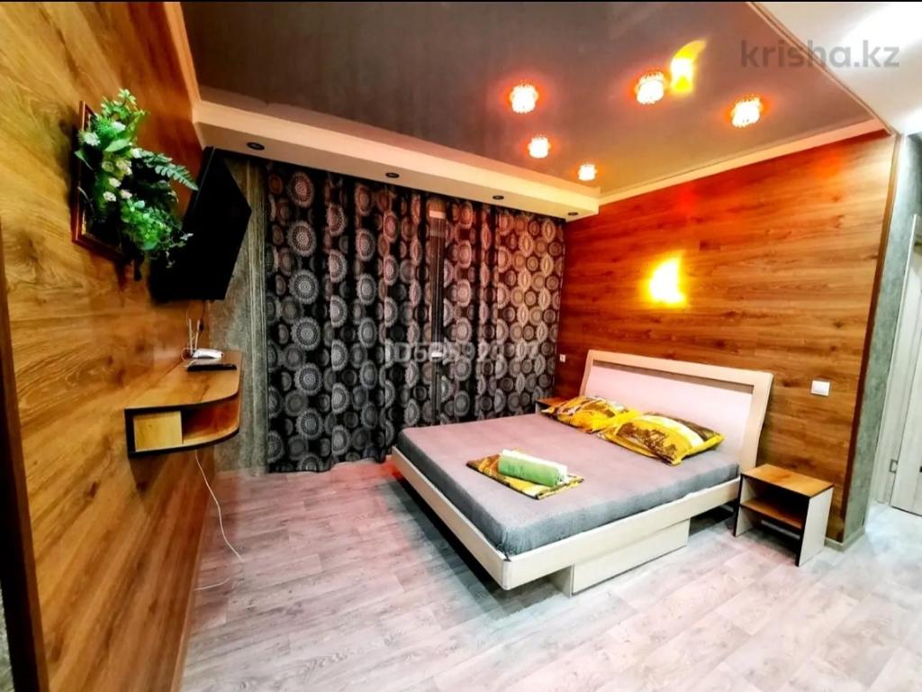 een slaapkamer met een bed en een houten muur bij Бектурова 15 in Pavlodar