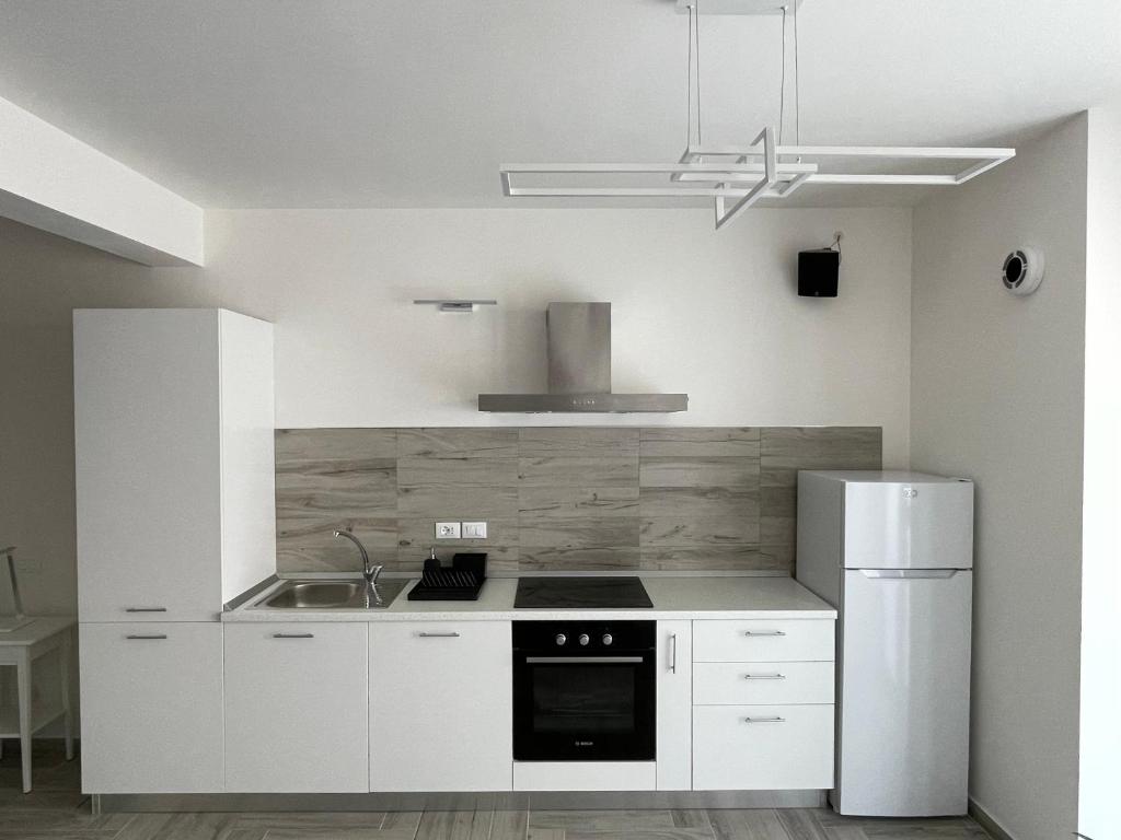 a white kitchen with a sink and a refrigerator at Holiday House in Ancona